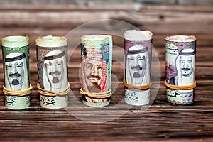 Closeup shot of Saudi Arabia money roll riyals with historic faces on a wooden surface