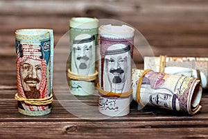 Closeup shot of Saudi Arabia money roll riyals with historic faces on a wooden surface