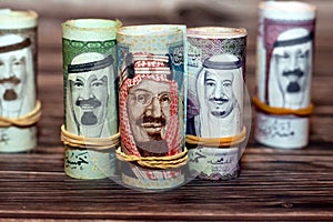 Closeup shot of Saudi Arabia money roll riyals with historic faces on a wooden surface