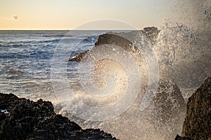 Closeup shot of a sea wave hits the rock on the shore and makes big splash