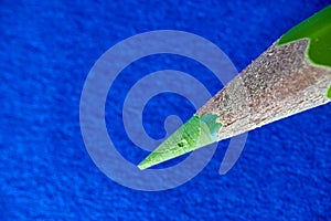 Closeup shot of a sharpened wooden green pencil on a blue background