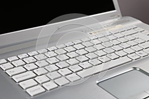 Closeup shot of a silver open laptop keyboard and touchpad