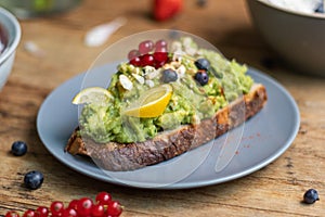 Closeup shot of a slice of brown bread with avocado pasta and berries