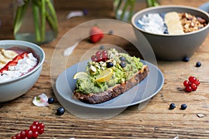 Closeup shot of a slice of brown bread with avocado pasta and a smoothie bowls