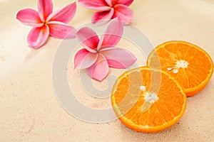 Closeup shot of sliced oranges next to pink plumerias