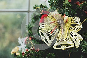 Closeup shot of small lovely seasonal festival decorative bright shiny golden bell hanging on Christmas green pine tree on x-mas