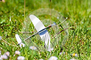 Closeup shot of a small plane toy on the ground covered in greenery under the sunlight