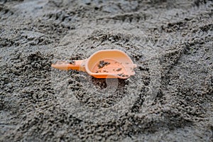 Closeup shot of a small plastic orange shovel on the sands of the beach