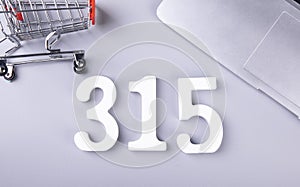 Closeup shot of small shopping cart, a laptop, and the number 315-concept of financial freedom