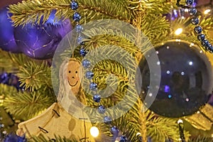 Closeup shot of a smiling female figure with balls hanging on a Christmas tress