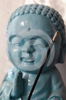 Closeup shot of smoking incense stick with buddha statue in the background