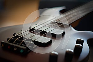 Closeup shot of a smooth body, pickups, bridge, knobs and strings of a bass guitar musical instrument with backlight