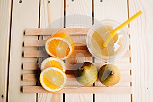 Closeup shot of a smoothie in a takeaway cup with fresh fruits on a slatted wooden tar