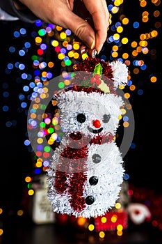 Closeup shot of a snowman Christmas tree ornament with blurred lights in the background