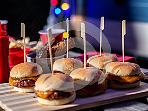 Closeup shot of some cheeseburgers on a wooden board on a table