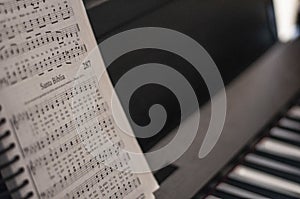 Closeup shot of a songbook at the top of a piano with a blurred background photo