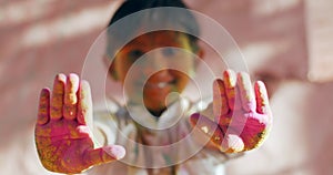 Closeup shot of a South Asian male child with colored hands during the Indian Holi Festival
