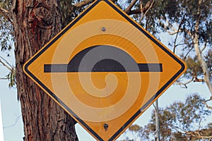 Closeup shot of a speed hump sign hanging on a trunk