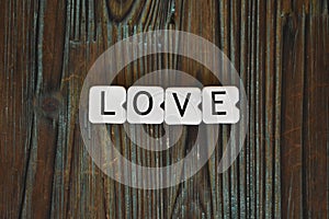 Closeup shot of square-shaped letters of the word love on a textured wooden table