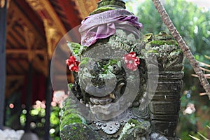 A closeup shot of a stone statue in Indonesia traditionally decorated with fabrics and flowers