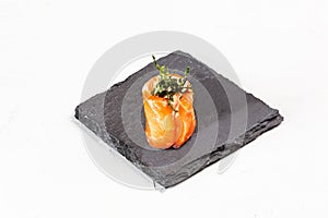 Closeup shot of a sushi roll on a black stone plate