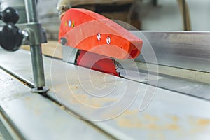 Closeup shot of table saw blade and orange blade guard. Electric woodworking tools in carpenter workshop.