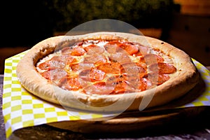 Closeup shot of a tasty pizza baked with sausage and sauce on a table