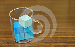 Closeup shot of tea glass filled with blue wooden toy cubes standing on a table