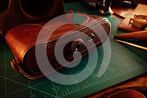 Closeup shot of thick leather camera case and tools for leathercraft on the table