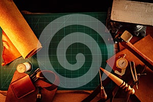 Closeup shot of thick leather sheets and tools for leathercraft on the table