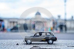 Closeup shot of a traditional black cab driving through the most famous landmarks in London