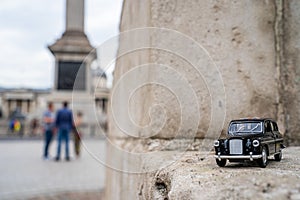 Closeup shot of a traditional black cab driving through the most famous landmarks in London