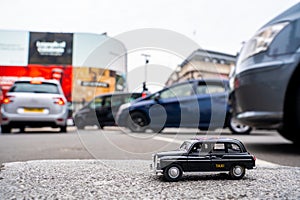 Closeup shot of a traditional black cab driving through the most famous landmarks in London