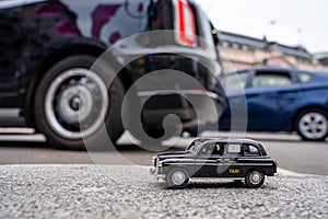 Closeup shot of a traditional black cab driving through the most famous landmarks in London