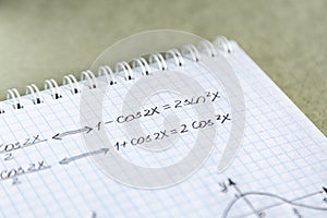 Closeup shot of trigonometric formulas written on a notebook paper