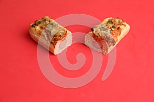 Closeup shot of two pieces of pizza loafs with sausage on a red background