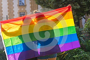 Closeup shot of two young Caucasian females holding LGBT pride flag outdoors