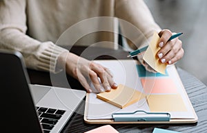 Closeup shot of university student hand holding pen, sticky note on planning board