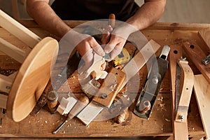 Closeup shot of unrecognizable faceless man carpenter making a handmade wooden toy in a home workshop, working on table among