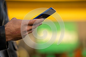 Closeup shot of an unrecognizable man holding mobile phone in hand, blurred background