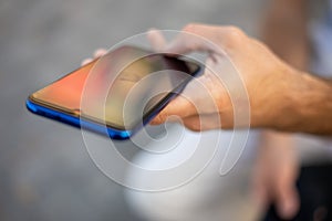 Closeup shot of an unrecognizable man holding mobile phone in hand, blurred background