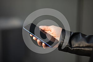 Closeup shot of an unrecognizable man holding mobile phone in hand, blurred background