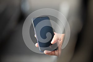 Closeup shot of an unrecognizable man holding mobile phone in hand, blurred background