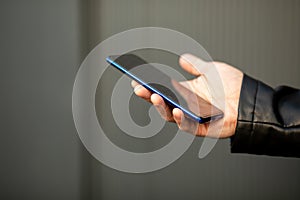 Closeup shot of an unrecognizable man holding mobile phone in hand, blurred background