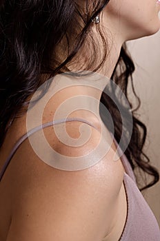 Closeup shot of unrecognizable tender young brunette woman& x27;s shoulder. Female body image, real skin, natural beauty.