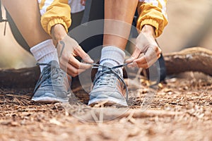Closeup shot of an unrecognizable woman tying the laces of her sneakers while out hiking in the woods.Unknown female