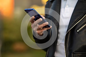 Closeup shot of an unrecognizable young man holding mobile phone in hand, blurred background