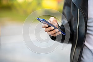 Closeup shot of an unrecognizable young man holding mobile phone in hand, blurred background