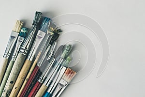 Closeup shot of used oil paint brushes in different colors on a white background