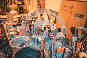 Closeup shot of various paintbrushes, tubes of paint, artistic tools and equipment in a studio